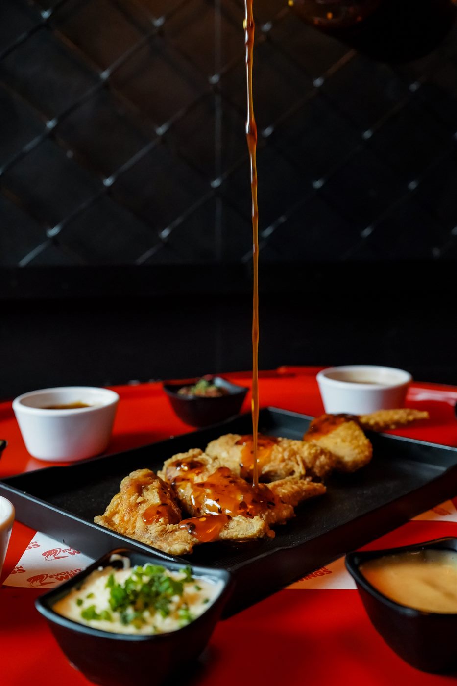 Alitas crujientes con salsa de la casa servidas en bandeja de Revolution Wings